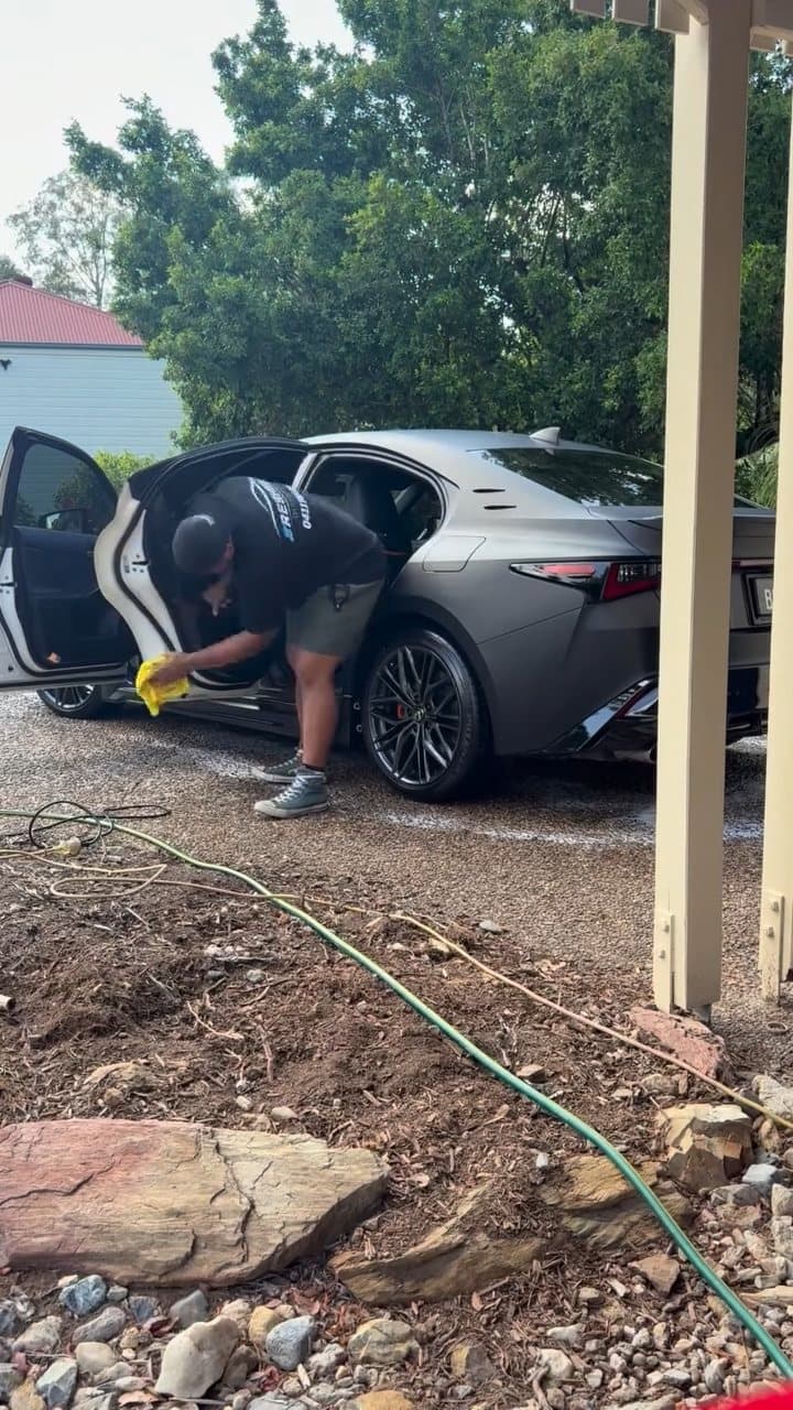 Alofa cleaning the door shut of a satin grey Lexus in a Brisbane driveway
